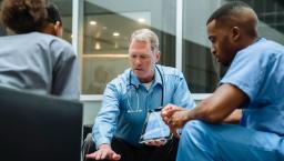 Three healthcare providers sitting around a table looking at a tablet